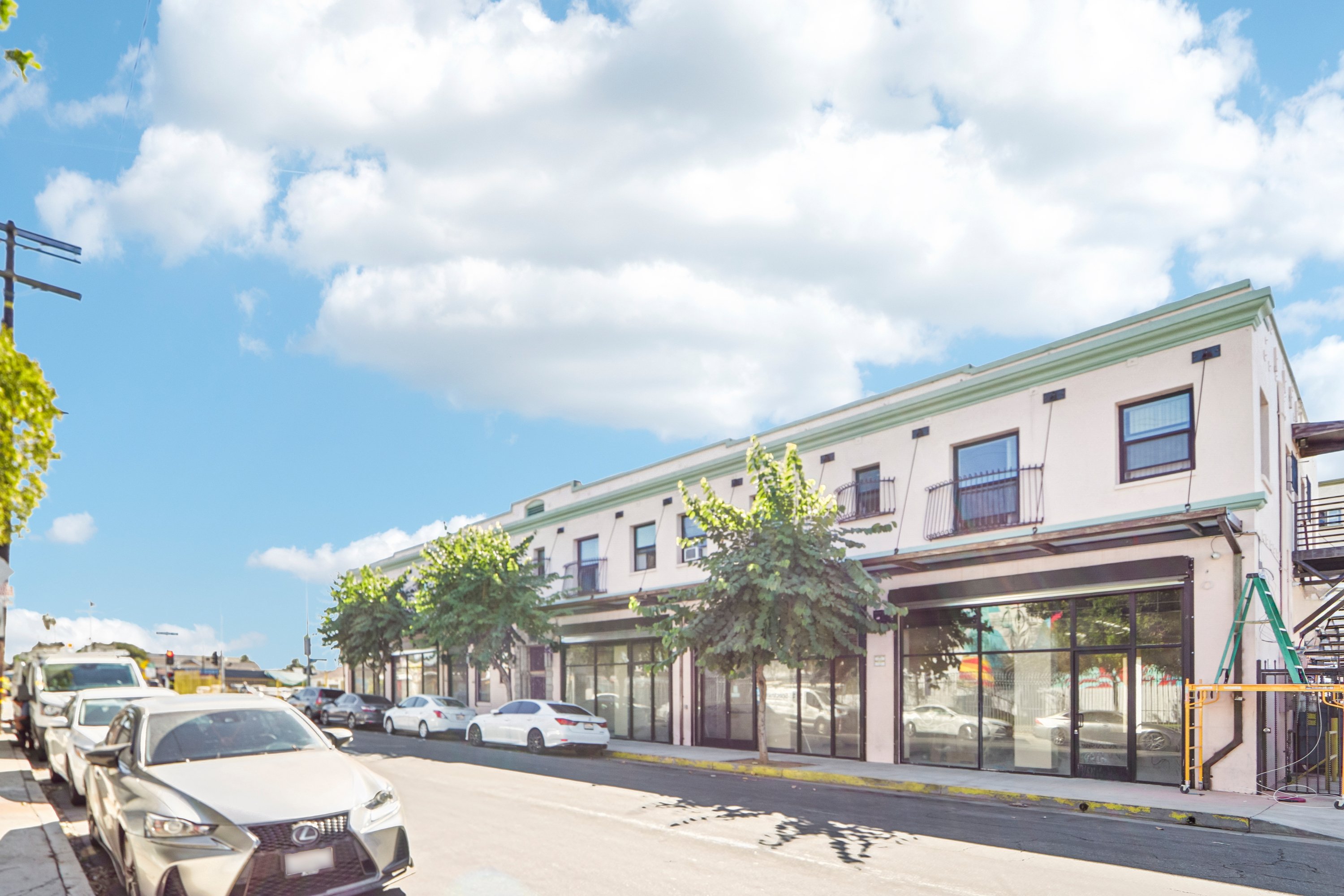A street view with cars parked on the side and a building with a green roof.